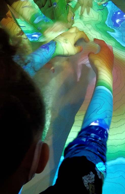 Sandbox with children's hands playing in sand.