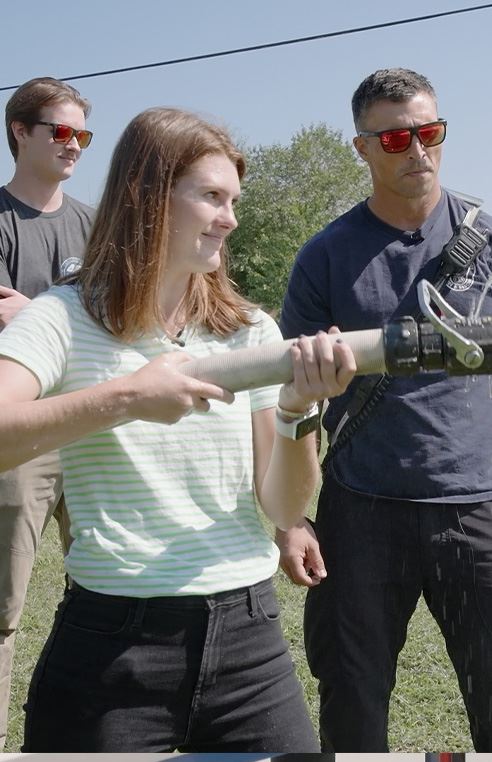 Kaelyn operating a fire hose